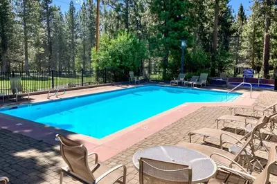 a large swimming pool with chairs and a table at Mammoth Green - 207 in Mammoth Lakes