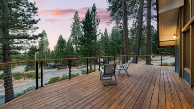 a deck with two chairs and a view of trees at Retreat with Lake Access Deck Modern Interior Agate Peak by Avantstay in Carnelian Bay