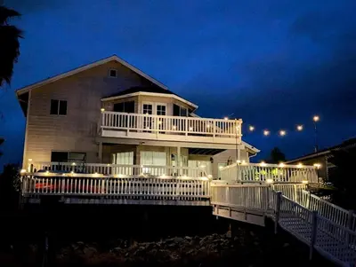 a large house with a large deck at night at 3 Bedrooms - Game Room - On the water in Discovery Bay