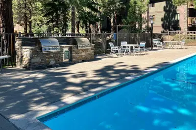 a swimming pool with a grill and tables and chairs at Summit 65 in Mammoth Lakes