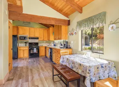 a kitchen with wooden cabinets and a table and a window at Yosemite Lodge 5BR Villa Hot Tub Game Room EV in Oakhurst
