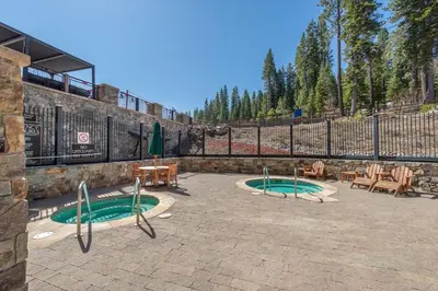 two green pools in a courtyard with tables and chairs at Ironhorse Northstar Condo condo in Truckee