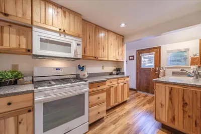 a kitchen with white appliances and wooden cabinets at Fred's Retreat cabin in Homewood