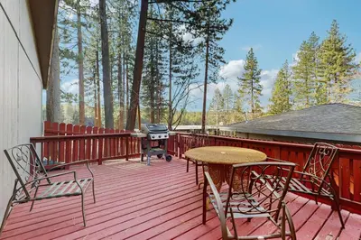 a wooden deck with a grill and a table and chairs at Mid-Century Tahoe Ranch House in South Lake Tahoe