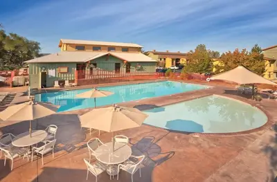 a large swimming pool with tables and chairs and umbrellas at Wyndham Angels Camp- 1 BR- Apartment with Resort Access in Angels Camp