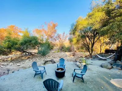 a group of chairs sitting around a fire pit at 2 Homes by the River in Three Rivers