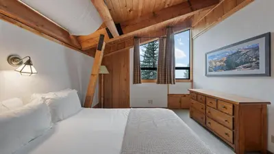 a bedroom with a white bed and two windows at Cozy Donner Lake Cabin w Kayaks Forest Views Fireplace Quick Ski Resort Access Donner Lake Refuge by AvantStay in Truckee