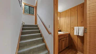 a staircase leading to a bathroom with a sink at Cozy Donner Lake Cabin w Kayaks Forest Views Fireplace Quick Ski Resort Access Donner Lake Refuge by AvantStay in Truckee