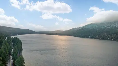 an aerial view of a river with trees and clouds at Cozy Donner Lake Cabin w Kayaks Forest Views Fireplace Quick Ski Resort Access Donner Lake Refuge by AvantStay in Truckee
