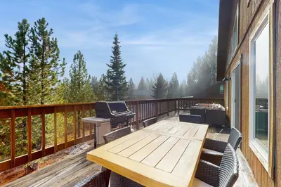 a deck with a wooden table and chairs on a house at Hillside Chalet in Truckee