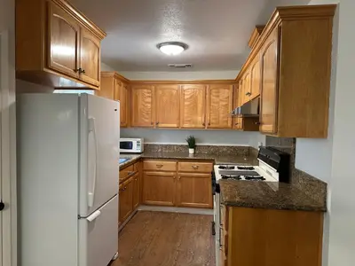 a kitchen with wooden cabinets and a white refrigerator at Downtown 2 Bedrooms Full Kitchen & Easy Parking in Sacramento