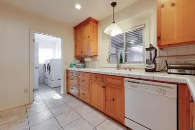a kitchen with wooden cabinets and a white refrigerator at Hot Tub, Patio and Outdoor Games at Visalia Home in Visalia