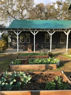a garden in front of a black building at Cozy Farm House with River access in Three Rivers