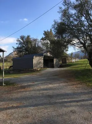 a barn with a building on the side of a road at Cozy Farm House with River access in Three Rivers
