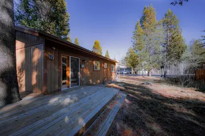 a house with a wooden deck next to a field at Bakersfield Basecamp - Meyers Escape in South Lake Tahoe