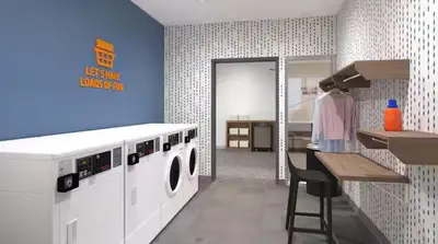 a laundry room with a washing machine and a stool at Home2 Suites By Hilton Carson City in Carson City