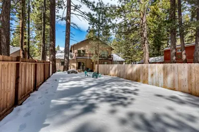a house with a fence in the snow at Meadow Chalet townhouse in South Lake Tahoe