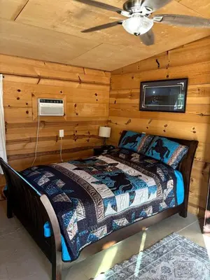 a bedroom with a bed in a room with wooden walls at Cozy Rustic Cabin on a Working Horse Ranch for a Unique Getaway in Granite Bay, California in Granite Bay