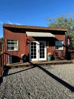 a small red house with a porch and a white door at Cozy Rustic Cabin on a Working Horse Ranch for a Unique Getaway in Granite Bay, California in Granite Bay