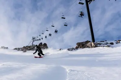a person riding a snowboard down a snow covered slope with a ski lift at Western Slopes Villas #7 condo in Mammoth Lakes