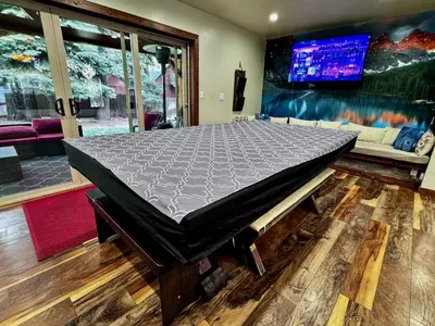 a bed in the middle of a room with a tv at Tahoe Cabin - Hot Tub, Fire Pit, Pool Table, minutes from Heavenly in South Lake Tahoe