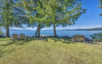 three benches sitting under trees next to a body of water at Lakeside Condo Close to Slopes Excellent Location in Tahoe Vista