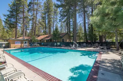 a large swimming pool with chairs and a house at Lakeside Condo Close to Slopes Excellent Location in Tahoe Vista