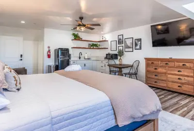 a bedroom with a large bed and a kitchen at The Four Daughters Inn in Oakhurst