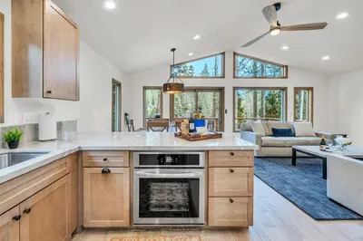 a kitchen with wooden cabinets and a living room at Tahoe City Retreat - Creekside Deck & Hot Tub in Tahoe City
