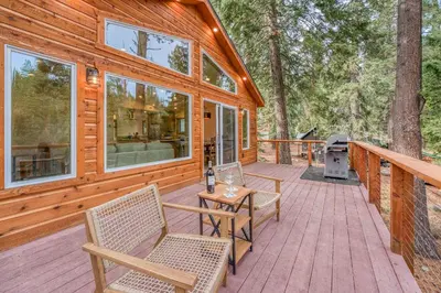 a cabin with a deck with chairs and a grill at Tahoe City Retreat - Creekside Deck & Hot Tub in Tahoe City