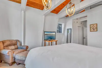 a bedroom with a large white bed and a chair at Cozy Cabin- Large Deck , Near the Slopes in Homewood