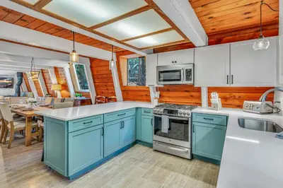 a kitchen with blue and white cabinets and a table at Cozy Cabin- Large Deck , Near the Slopes in Homewood