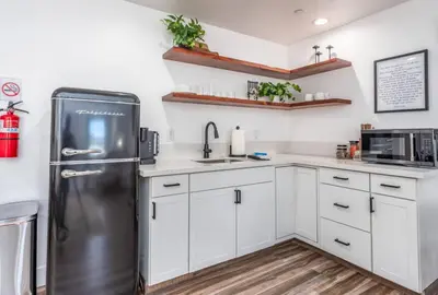 a kitchen with white cabinets and a stainless steel refrigerator at Peytons Luxury Suite at The Four Daughters Inn in Oakhurst