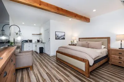 a bedroom with a large bed and a kitchen at Kassidy Suite at The Four Daughters Inn in Oakhurst