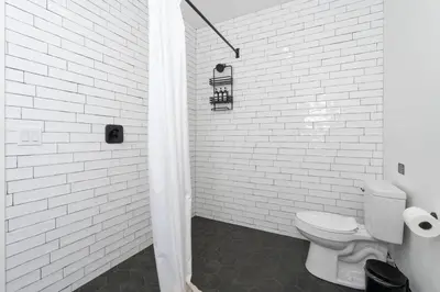 a bathroom with a toilet and a white brick wall at Kassidy Suite at The Four Daughters Inn in Oakhurst