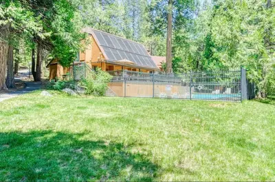 a house with a fence in front of a yard at Little Ski Lodge-Across from Spa & Sauna in Shaver Lake