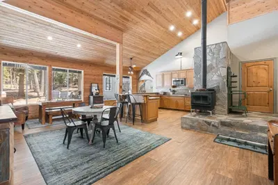 an open kitchen and living room with a table and chairs at Lazy Bear Lodge Rustic Luxe Villa with spa & gameroom in Shaver Lake