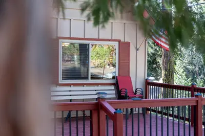 a porch with a bench and a red chair at Smoke Tree-Newly Updated Family Retreat in Shaver Lake