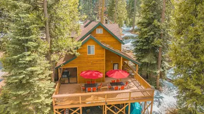 an aerial view of a tree house with two red umbrellas at Bear Bottoms Family Cabin-Huge GAME ROOM in Shaver Lake