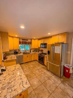 a kitchen with yellow cabinets and stainless steel appliances at Bear Bottoms Family Cabin-Huge GAME ROOM in Shaver Lake