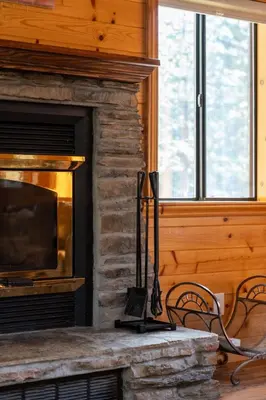 a stone fireplace with two chairs and a television at Black Diamond-Family Pet Friendly & Near China Peak in Big Creek