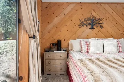 a bedroom with a wood paneled wall and a bed at Wyldwood-Family Friendly-LOFT & BAR in Shaver Lake