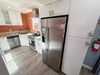 a stainless steel refrigerator in a kitchen with white cabinets at Charming Lake Tahoe Getaway 30 Plus Days Bookings Only Accepted in Zephyr Cove