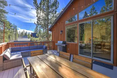 a deck with a wooden table and bench on a house at Evergreen Getaway Pet Friendly in SLT w Hot Tub in South Lake Tahoe