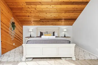 a bedroom with a white bed and wooden ceilings at Apple Blossom Lodge-Family Friendly Cabin in Shaver Lake