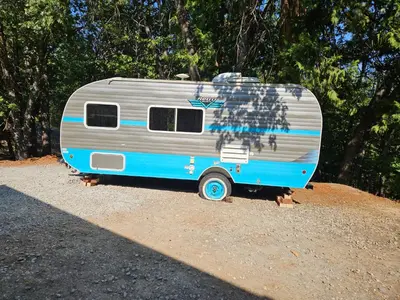 a blue and silver trailer parked on a dirt field at Gold Rush Historical Resort in Sonora