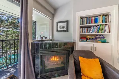 a living room with a fireplace and a book shelf at Guest Favorite Spacious Remodeled 2 Bdrm 2 Ba Mountain Views in Mammoth Lakes
