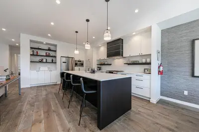 a kitchen with white cabinets and a black island with bar stools at Starfall Run at Palisades by Tahoe Getaways - Luxury 3BR w Ski Shuttle, A/C & Bonus Room! in Alpine Meadows