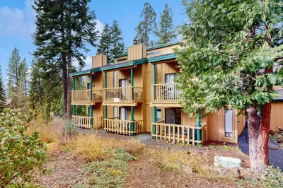 a large yellow house with balconies and trees at Cozy Kings Run Condo in Tahoe Vista