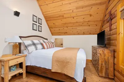 a bedroom with a bed and a flat screen tv at Happy Trails-Family Style Log Home Winter Escape in Shaver Lake